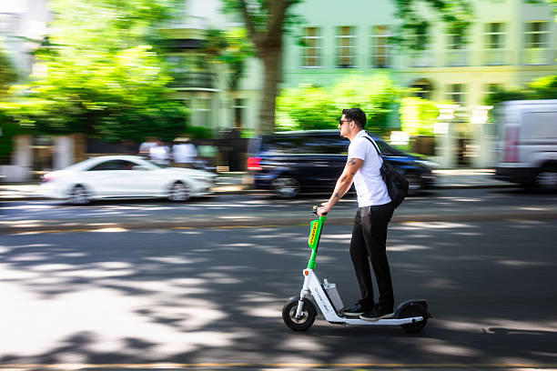 London, UK - 13 May, 2025: action shot depicting a man riding fast on a Lime electric scooter on a road in central London, UK. The panning technique used means the background is blurred, giving the impression of high speed.