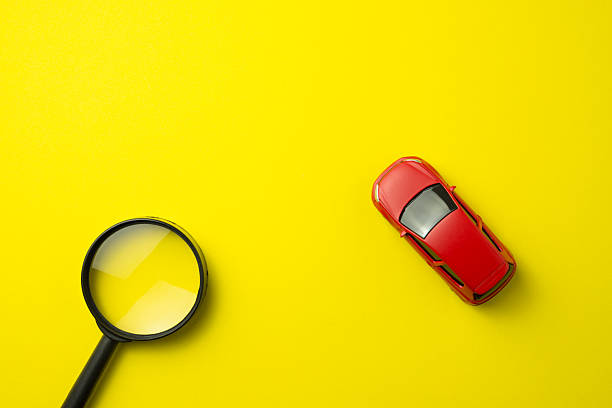 istock Red car and magnifying glass on yellow background with copy space. 2215261146