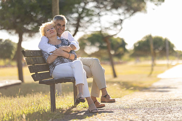 istock Happy senior couple embracing on park bench during retirement 2215262363