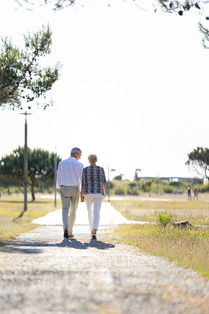 istock Senior couple walking away on a sunny path holding hands 2215263559