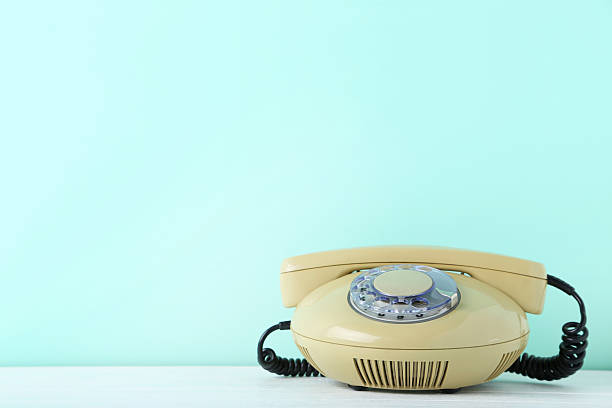 istock Beige retro telephone on white wooden table 2215272490