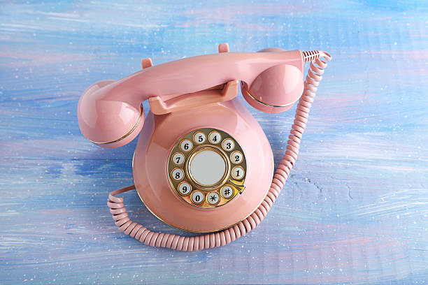 istock Pink retro telephone on blue wooden table 2215273645