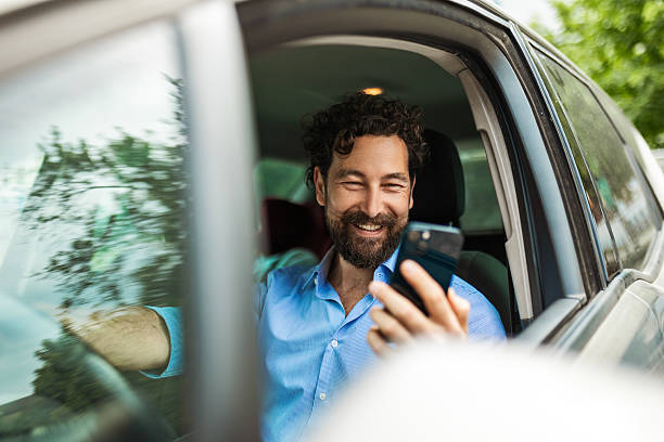 istock Businessman in Car Reading Message on Smartphone 2215275729