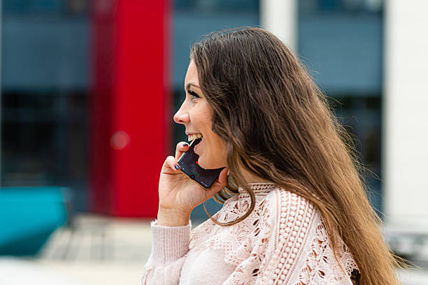 istock Young Woman Smiling While Talking on Phone Outside Modern Building During Daytime 2215279701
