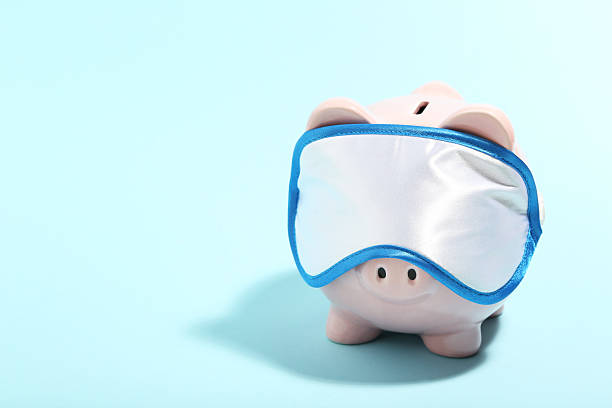 istock Piggybank with sleeping mask on blue background. Minimalism concept 2215280259