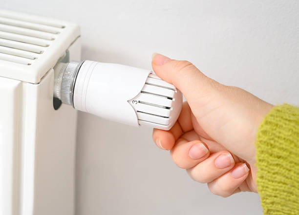 istock Woman's hand adjusting radiator thermostat to regulate room temperature. 2215280807