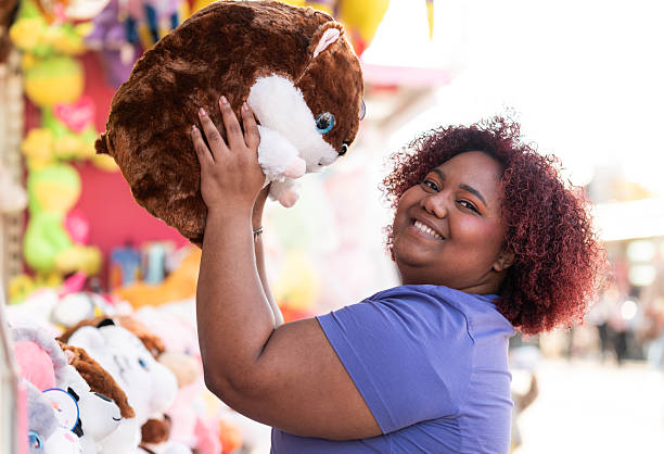 Young woman enjoying a day at the funfair, happily holding a large plush toy won from a game stall, radiating joy and excitement