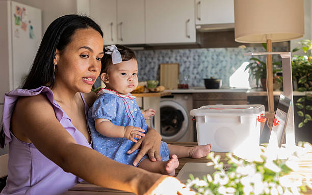 istock Latin mom working from home while holding baby daughter 2215283514