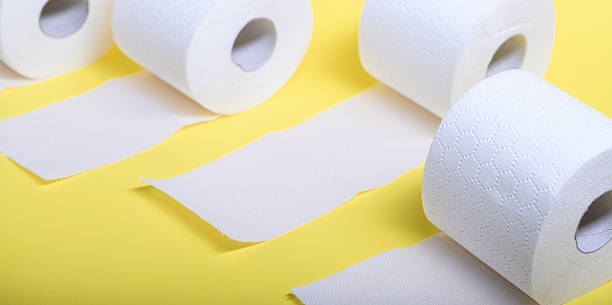 istock Soft white toilet paper rolls on a vibrant yellow surface, emphasizing hygiene needs 2215291742