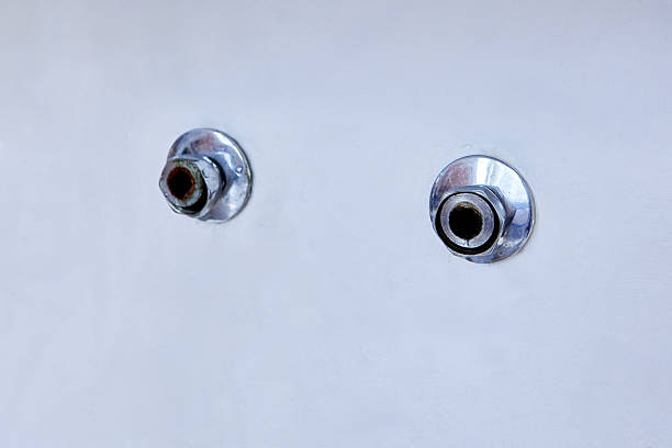 istock Two exposed metal pipe outlets with chrome escutcheons protrude from smooth white wall after removal of old wall mounted faucet, showing slight corrosion. 2215292514