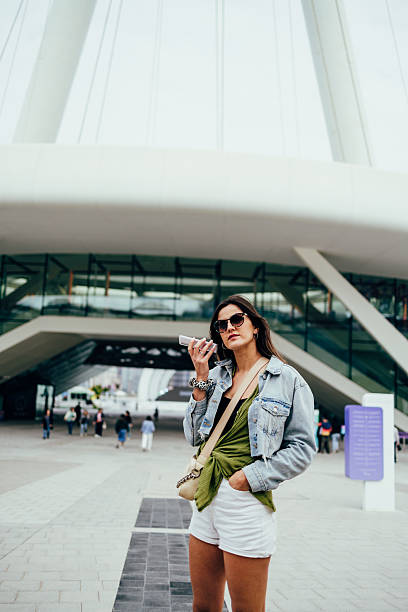 istock Stylish young woman is using her smartphone outdoors in a modern city setting 2215296293