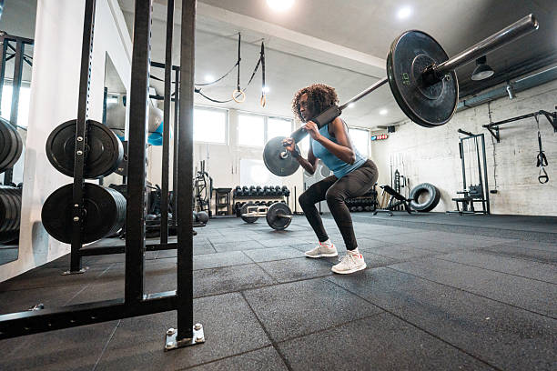 istock Mid Adult Black Female Lifting Weights in Bright Modern Gym with Determined Expression 2215301616