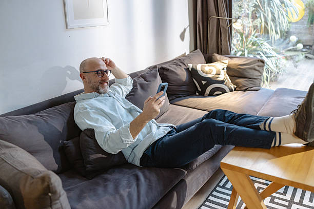 istock Man relaxing on a sofa at home using his smartphone 2215302849