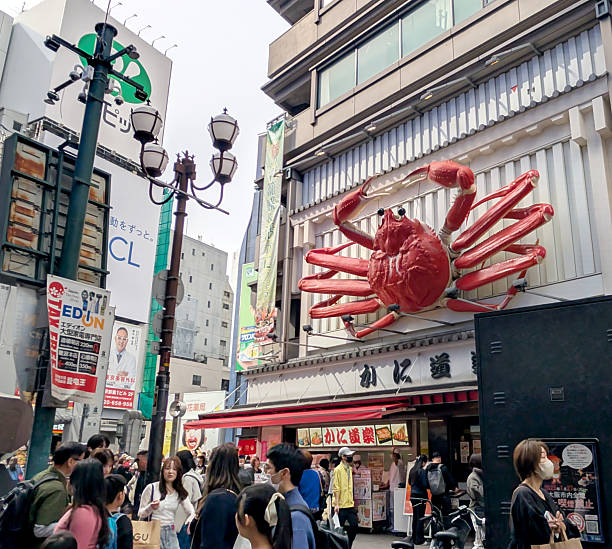 Osaka, Japan - April 12, 2025: The famous giant crab watches over tourists on Dotonbori Street. Spring afternoon in the Chuo Ward with an overcast sky.