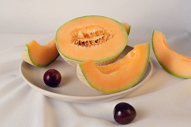 Peach, plum and melon on wooden table still life