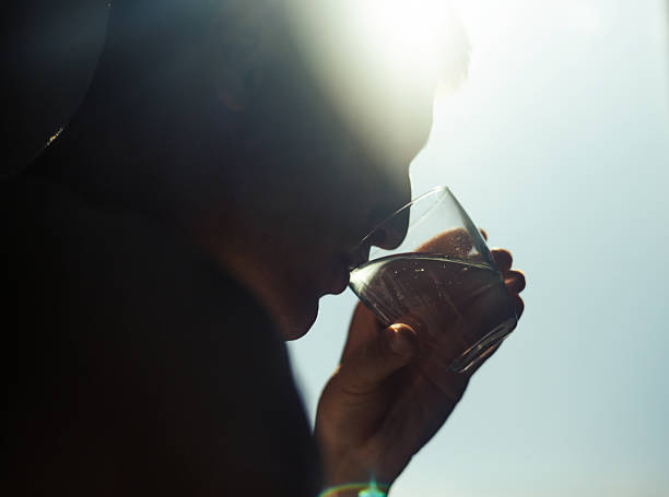 A portrait of a man sipping a drink in a brightly sunlit environment, with visible lens flares and highlights creating a dynamic atmosphere.
