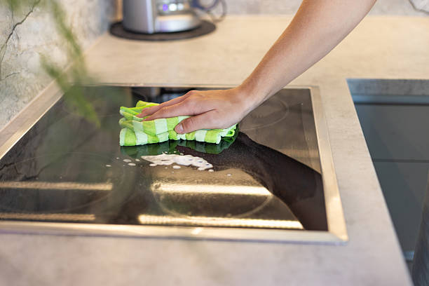istock Person Cleaning a Kitchen Stovetop Surface With a Cloth 2215311655