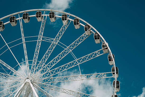 istock Ferris wheel against a blue sky with clouds, showcasing its structure and cabins during daylight hours 2215312209