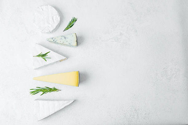 istock Delicious selection of assorted cheeses with fresh herbs on a white surface 2215312616