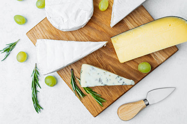 istock Cheese platter with assorted cheeses, grapes, and herbs on wooden board 2215312618