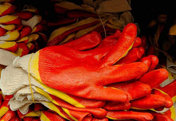 variety vibrant red and yellow work gloves are neatly stacked together in hardware store. these gloves are designed for protection during outdoor or construction activities. closeup.