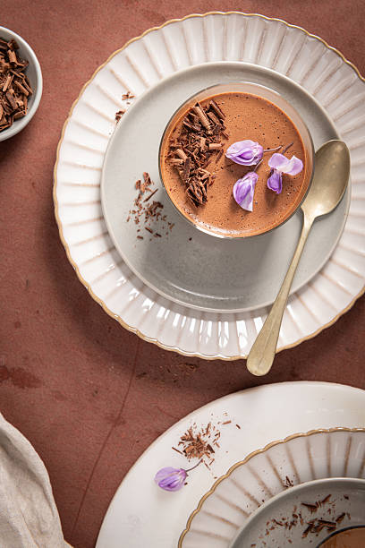 istock An overhead view with a vertical composition featuring two chocolate mousses in glasses, styled on plates with a spoon, bowl of shavings, and cloth. 2215314531