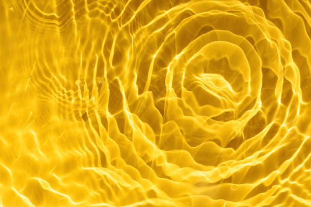 Abstract background of yellow water with ripples under sunlight. Top view, flat lay. Creative background concept for business, cosmetics advertising. Copy space