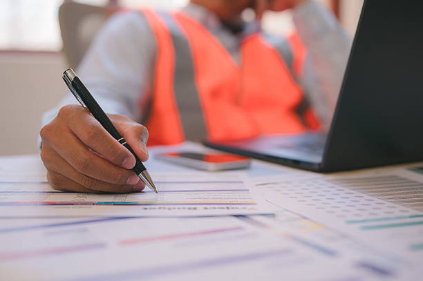 istock An engineer or foreman working on site sitting on desk in office using pen and computer analysing data charts paper work 2215326775