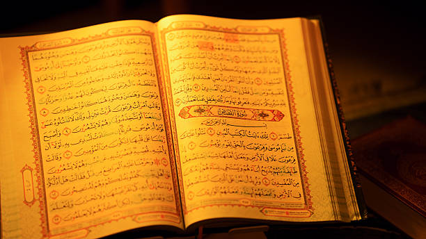 istock Open Holy Quran featuring intricate Arabic text and decorative borders illuminated with warm light symbolizing Islamic devotion 2215336388
