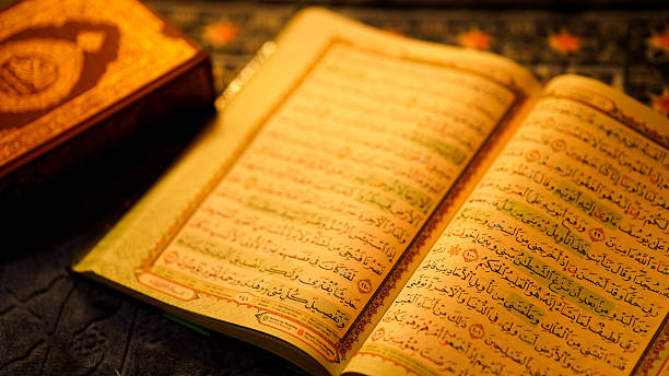 istock Quran open to highlighted Arabic verses with colorful tajweed rules under soft warm light representing Islamic learning and worship 2215336453