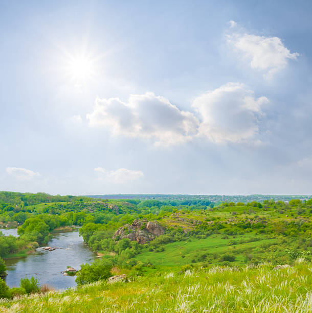 river flow among green hills under blue cloudy sky at the summer sunny day