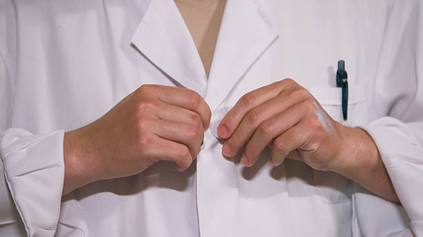 a closeup of a person adjusting a white lab coat in preparation for a professional wellness or medical session, emphasizing attention to detail and hygiene in a clean environment.