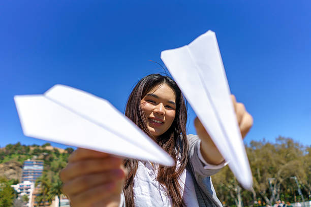 istock Young woman playing with paper planes in a park 2215342687