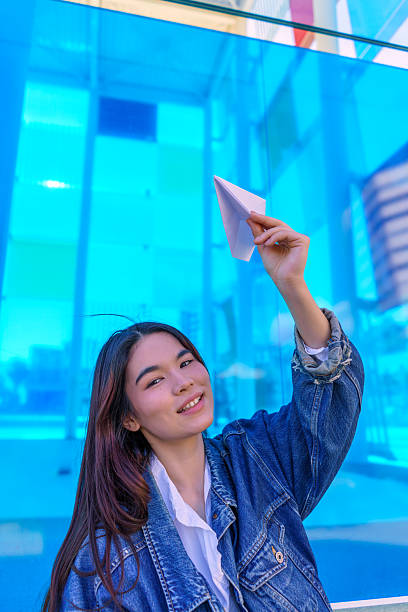 istock Young woman launching paper airplane with blue background 2215342718