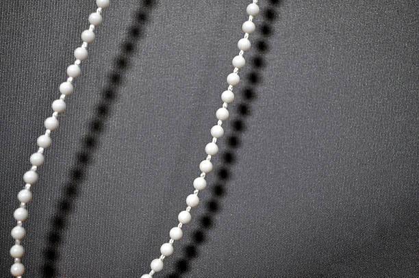 Minimalistic close-up of a beaded pull chain casting soft shadows on a textured fabric background. repetitive pattern, neutral tones, and a modern aesthetic minimalism, control  interior design