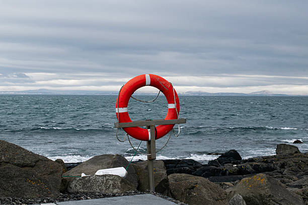 A vibrant red lifesaver by the rocky coastline of Akranes with a cloudy atmosphere