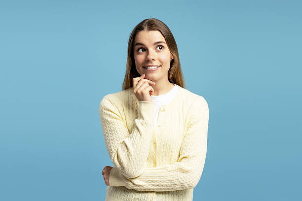 istock Smiling, young woman planning and thinking on blue background 2215351627