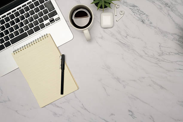 istock Flat lay of office essentials including earphones, coffee, and a blank notebook on work desk 2215351939