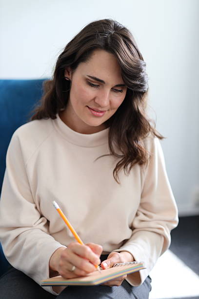 istock Young caucasian female writing with pencil in notebook at home 2215355986