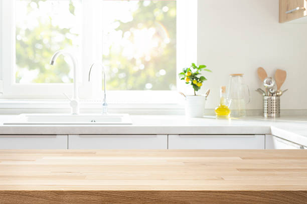 istock Wood table top for product montage on blur kitchen sink and window interior background 2215356917