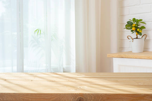 istock Wooden planks table with sunlight shadows for product display on curtained window interior background 2215356927