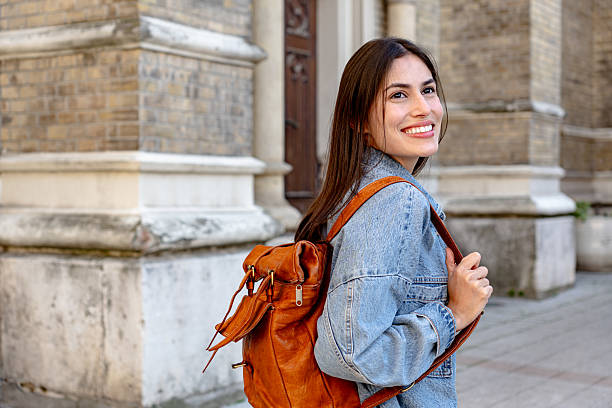 istock Young woman with backpack smiling near university building 2215357666