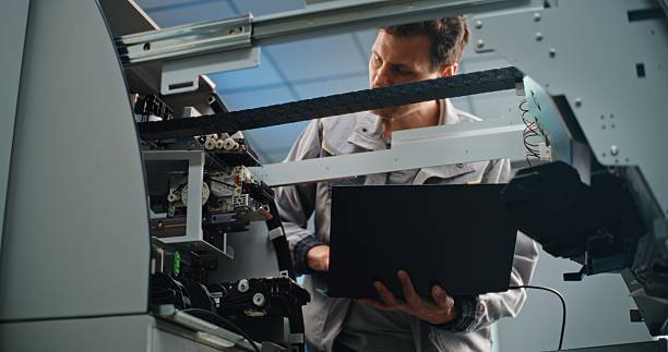 istock Technician Servicing ATM Machine in Airport Terminal, Using Laptop 2215361619