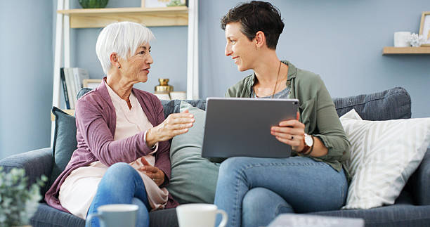 istock Tablet, learning and woman with senior mother on sofa for chatting, scrolling or networking. Digital technology, teaching and female person helping elderly mom with online communication in home. 2215364363