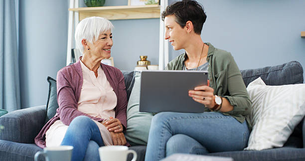 istock Tablet, teaching and woman with senior mom on sofa for chatting, scrolling or networking. Digital technology, learning and female person helping elderly mother with online communication in home. 2215364366