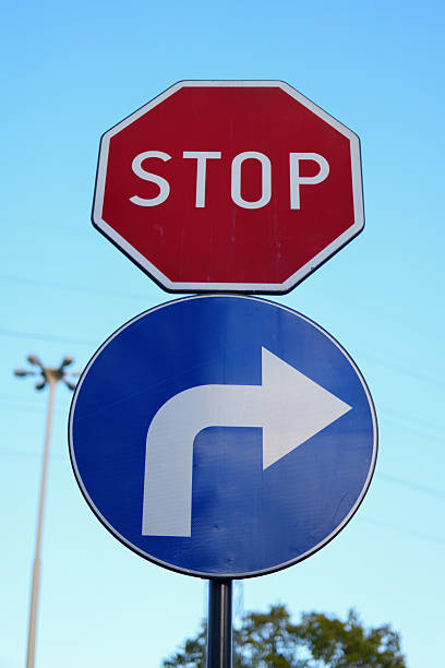 Road signs including a red stop sign and a blue circular sign with a white arrow indicating a mandatory right turn.