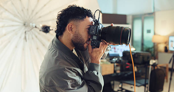 istock Photographer, camera and man in studio, equipment and backstage with skills, creativity and project. Person, entrepreneur or guy with professional, business for pictures and media agency for magazine 2215367777