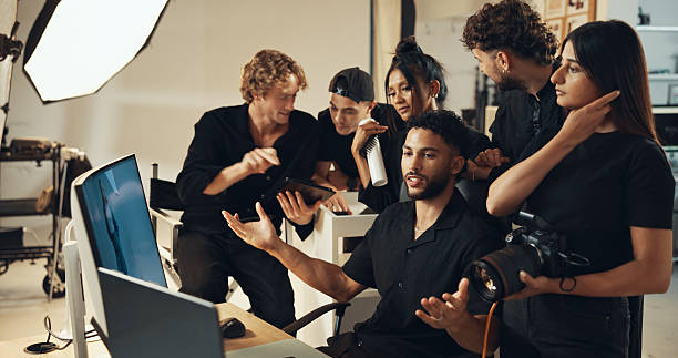 istock People, photographer and review on studio computer for production results, talking and teamwork. Staff, photoshoot and tech to check for fashion photography, magazine catalog and filming process 2215367933