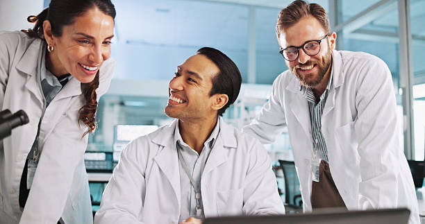 istock Team, scientist and discussion with laptop in lab for cure discovery, breakthrough or happy for innovation. Science worker, medical collaboration or computer with test results for healthcare research 2215368566