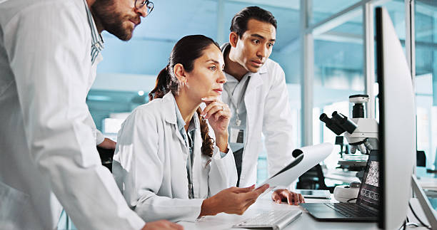istock Teamwork, notes or scientists on computer for medical breakthrough, clinical trial or DNA discovery. People, biology testing or science research in lab with paper, bacteria results or medicine cure 2215368637